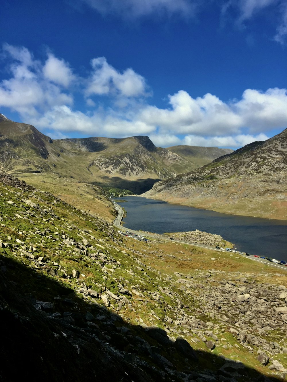 a lake surrounded by mountains under a cloudy blue sky