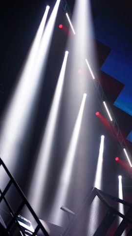 Wide shot of a concert stage being assembled with bright halogen lights