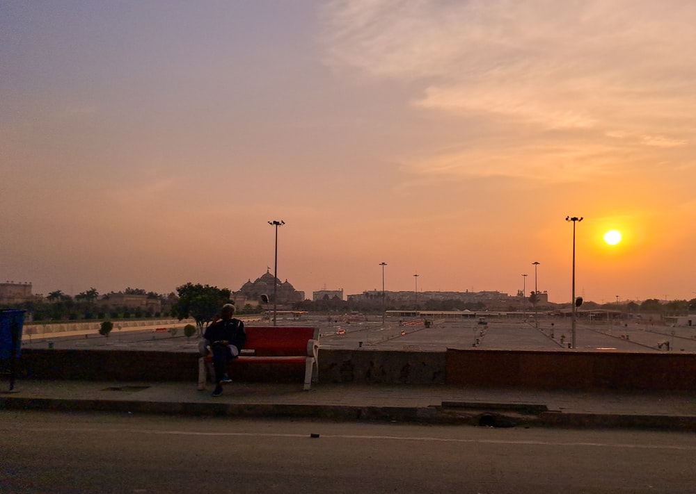 a person sitting on a bench in a parking lot