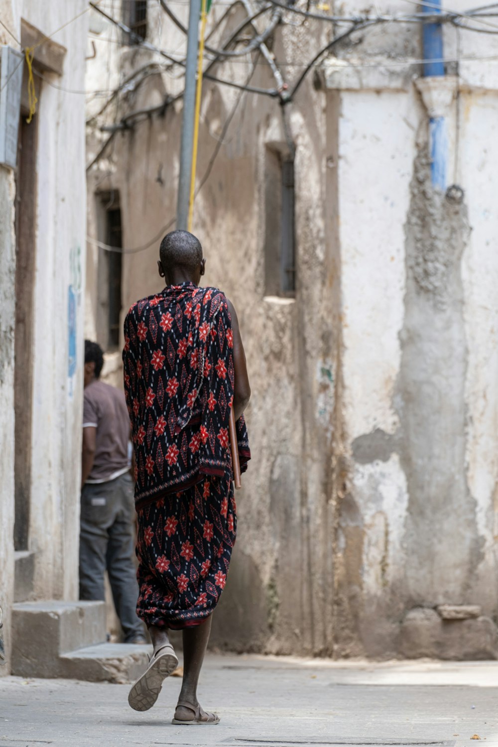 a man walking down a street next to a building