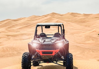 a red four passenger vehicle driving through the desert