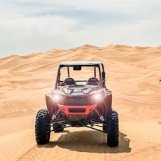 a red four passenger vehicle driving through the desert