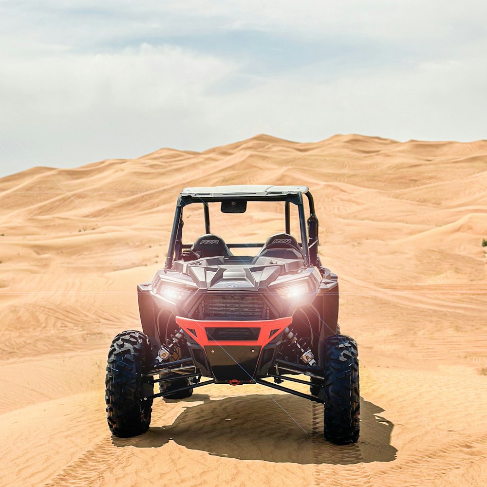 a red four passenger vehicle driving through the desert