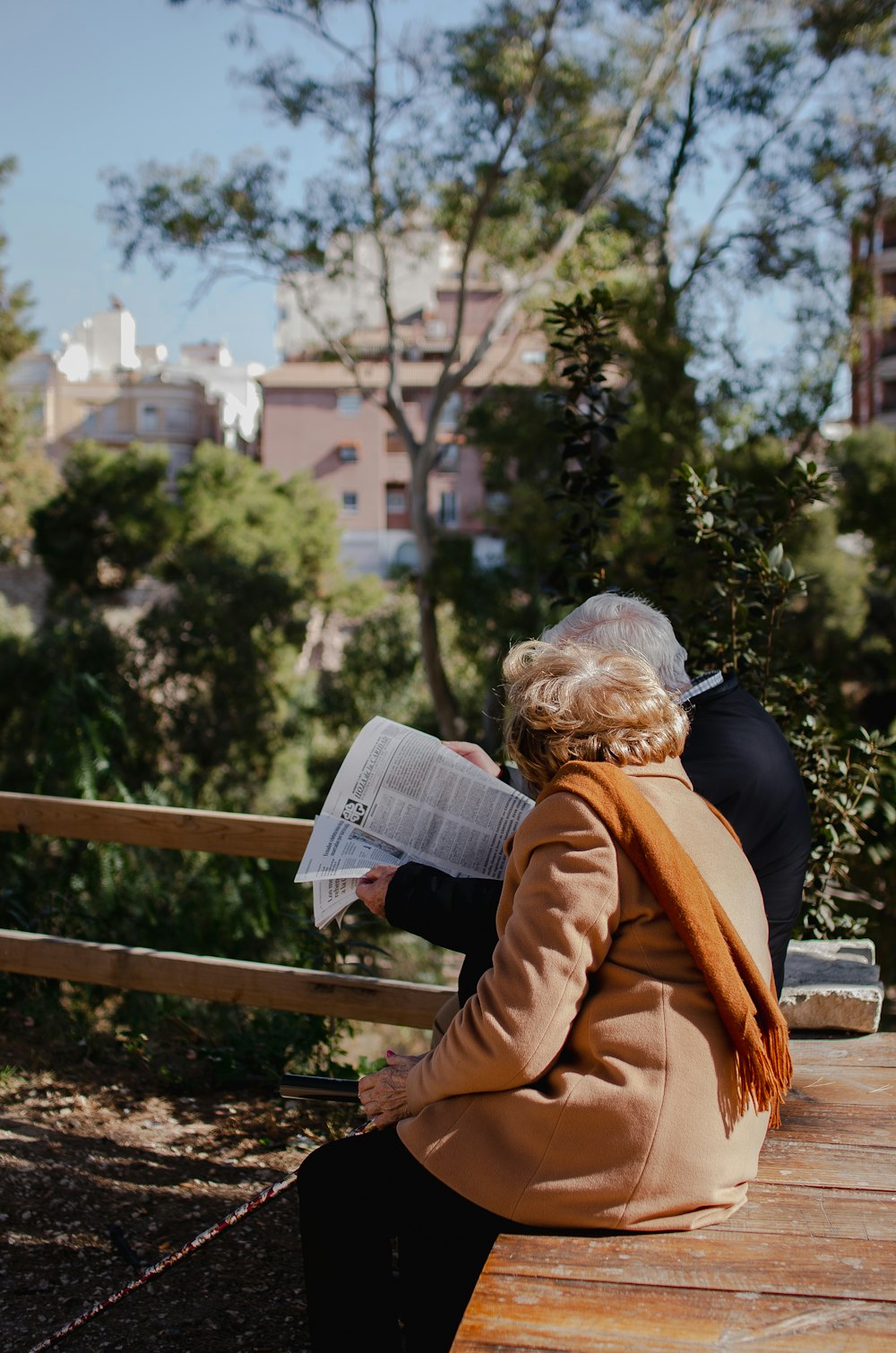 a woman sitting on a bench reading a newspaper