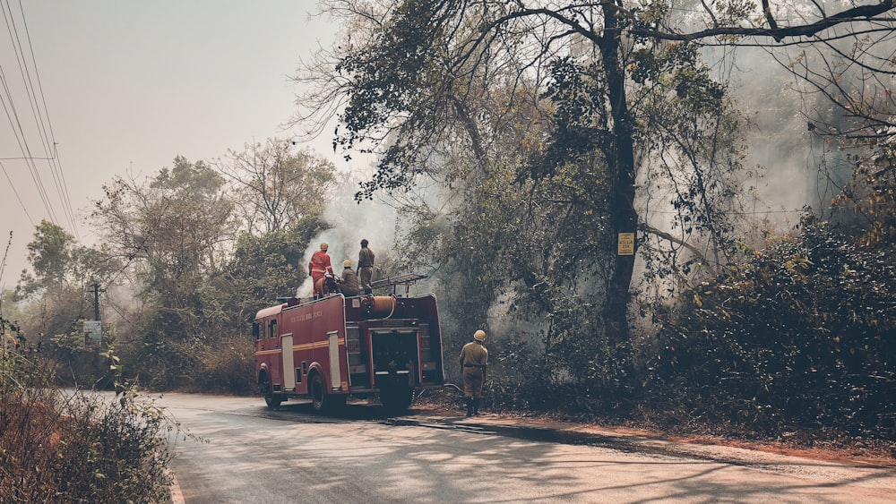 a red fire truck driving down a street next to a forest