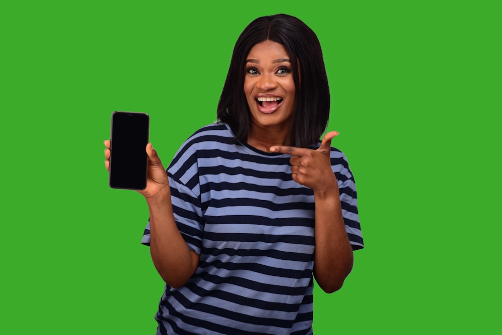 a woman in striped shirt holding up a cell phone