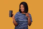A smiling woman holding a smartphone displaying the infoweb.net app outdoors.