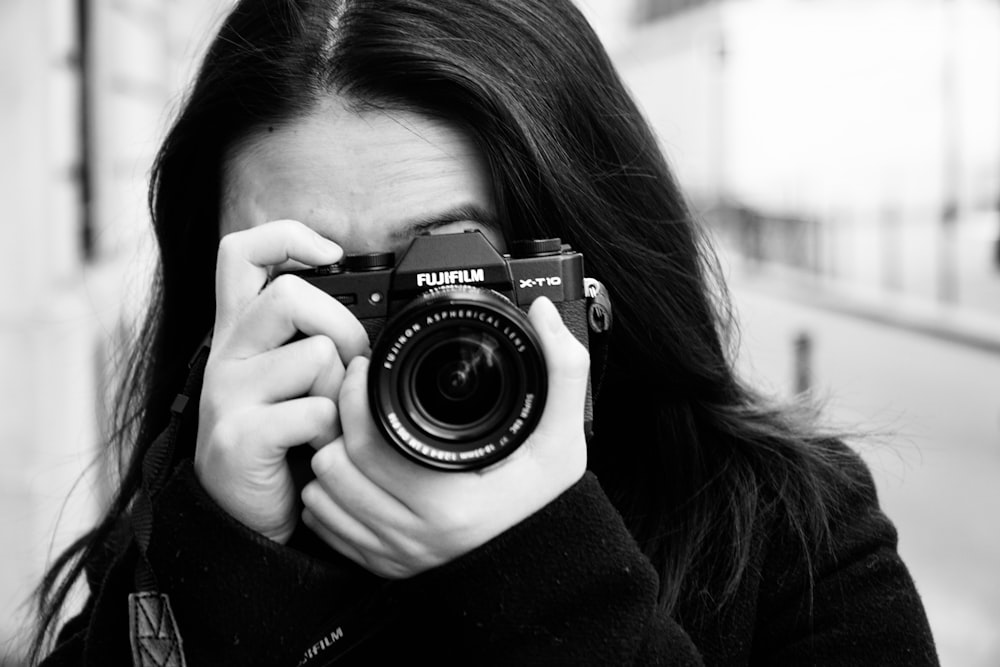 a woman holding a camera up to her face