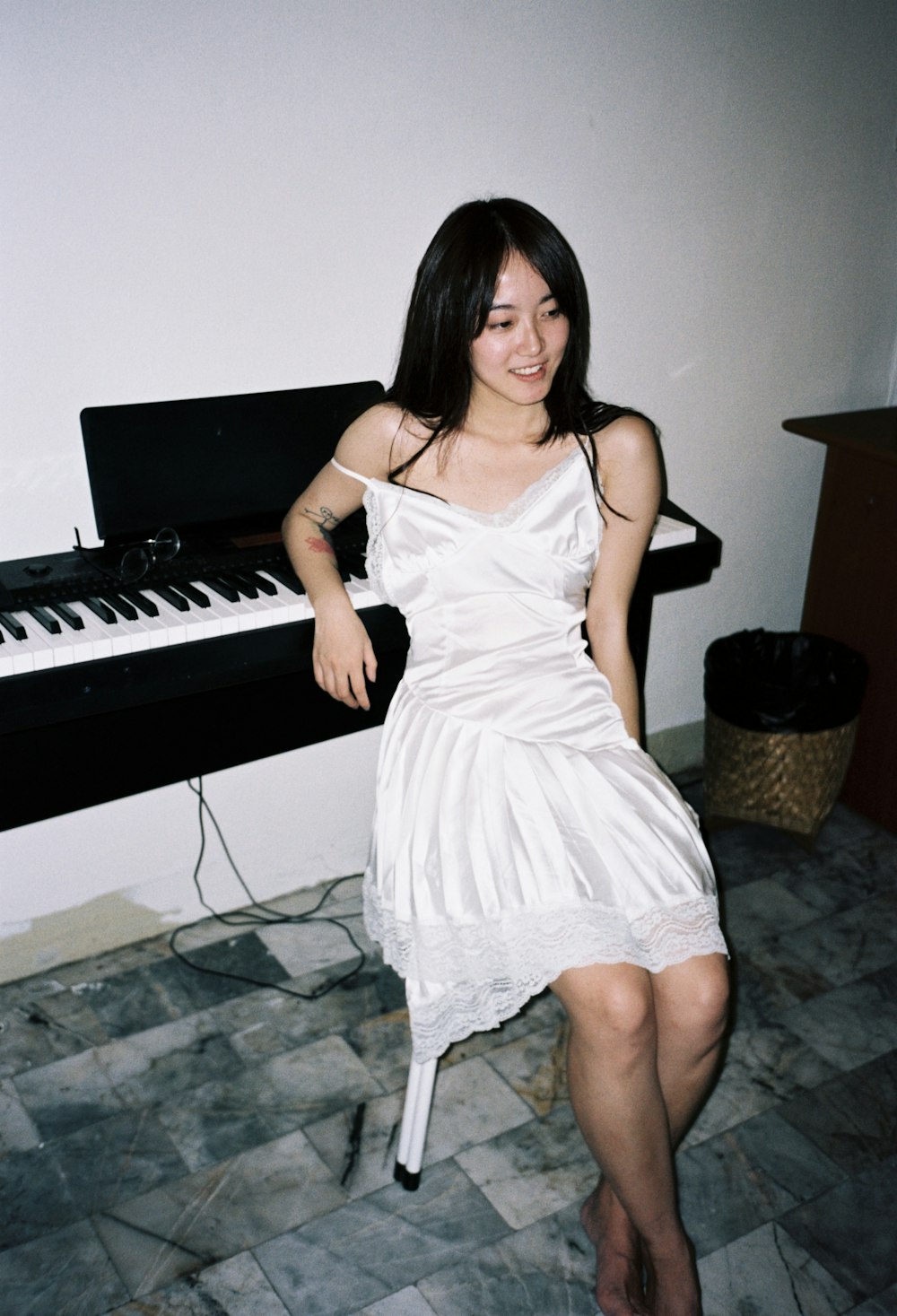 a woman in a white dress sitting in front of a piano