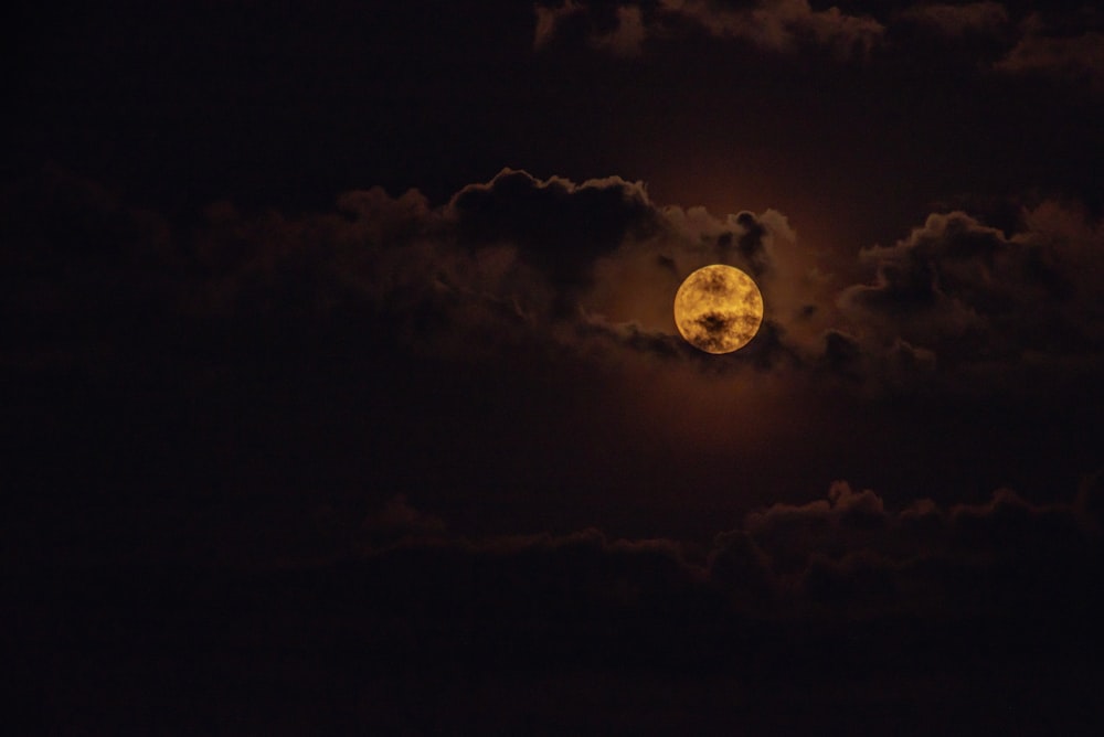 a full moon is seen through the clouds