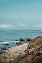 A peaceful coastal scene with anglers practicing bottom fishing on rocky shores.