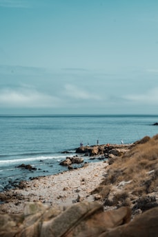 A peaceful coastal scene with anglers practicing bottom fishing on rocky shores.