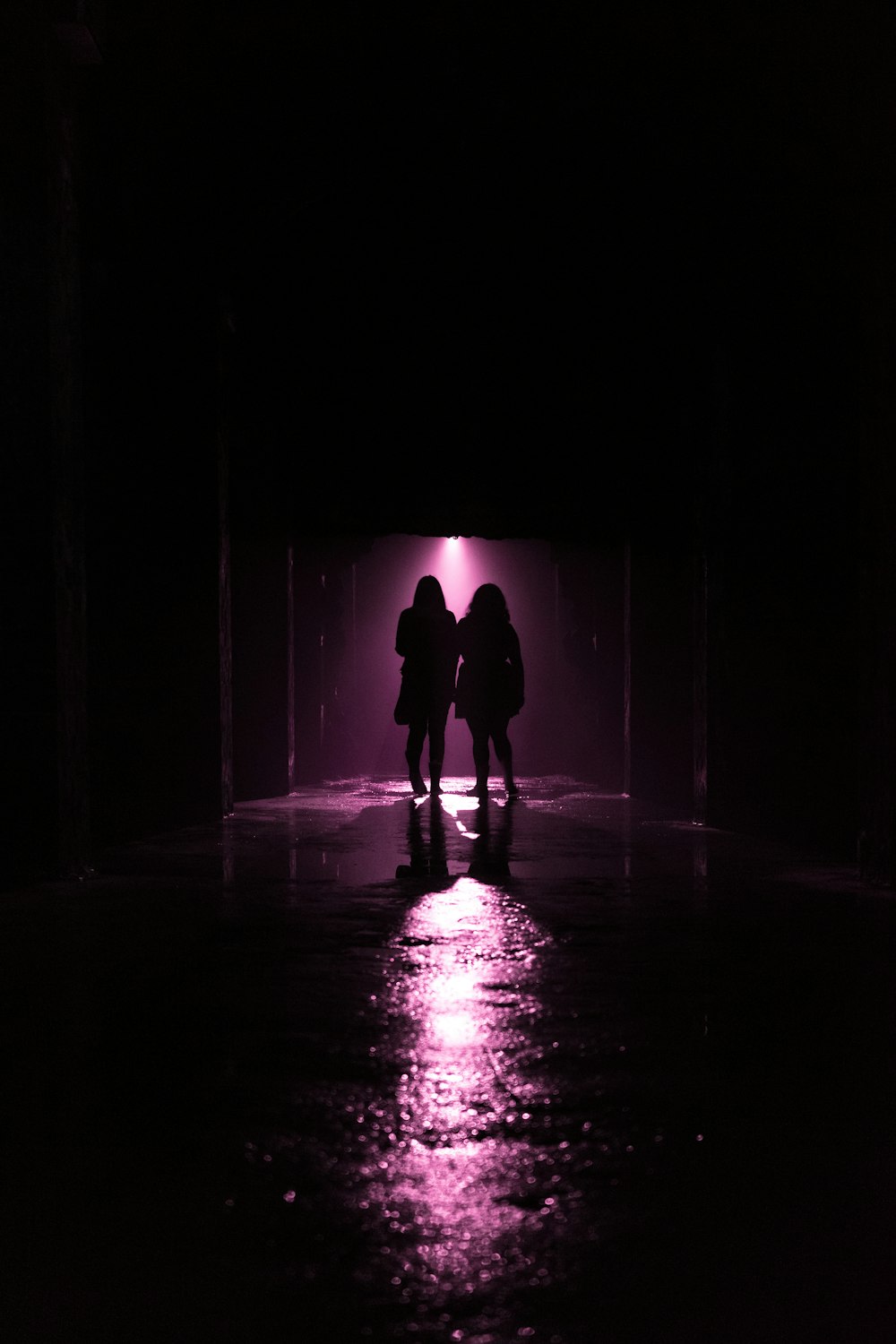a couple of people standing in a dark tunnel