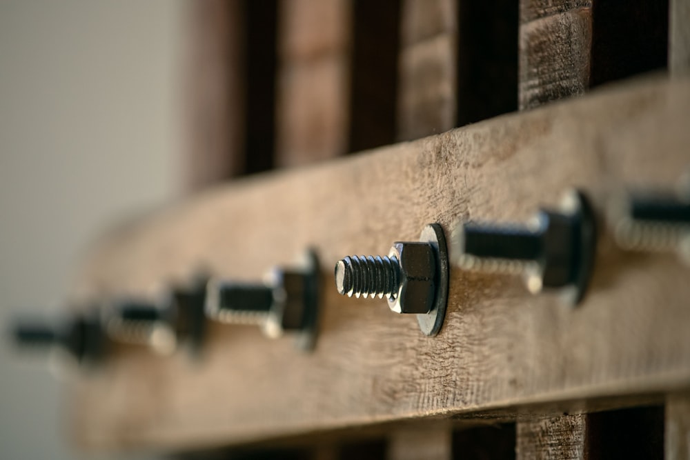 Un primer plano de un montón de tornillos en una tabla de madera