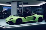 A sleek, lime green sports car is displayed in a well-lit showroom. The car's doors are open, showcasing its luxurious interior. In the background, other high-performance vehicles are partially visible, creating an atmosphere of elegance and sophistication.