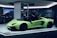 A sleek, lime green sports car is displayed in a well-lit showroom. The car's doors are open, showcasing its luxurious interior. In the background, other high-performance vehicles are partially visible, creating an atmosphere of elegance and sophistication.