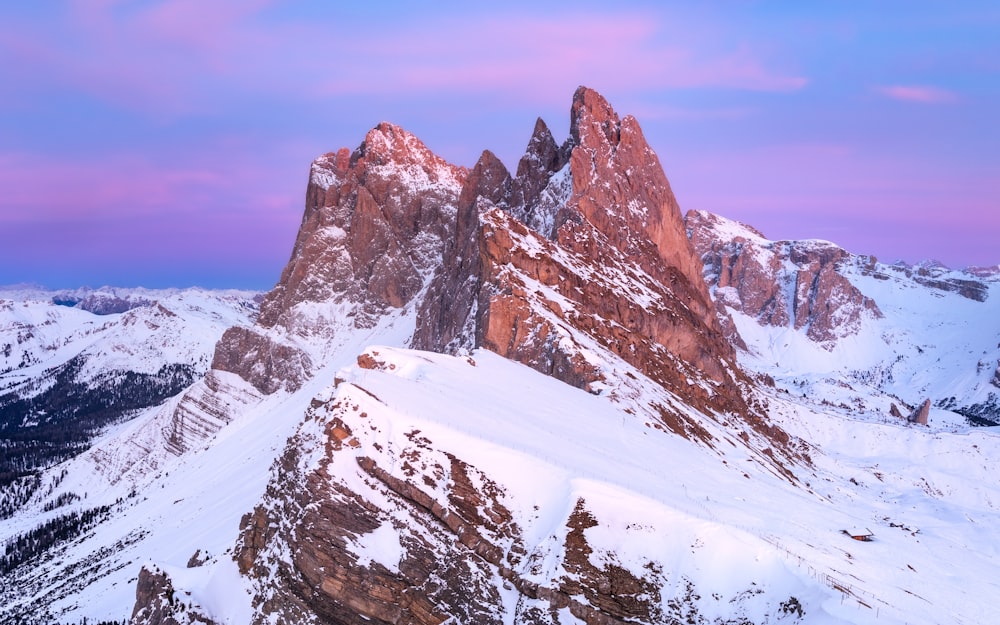 a mountain range covered in snow under a purple sky
