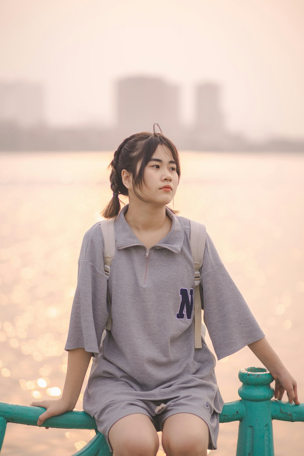 a woman sitting on a rail next to a body of water