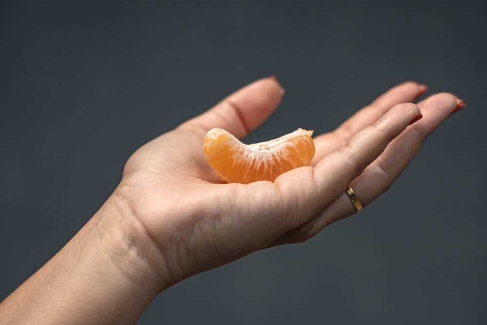 una persona sosteniendo una naranja en la mano