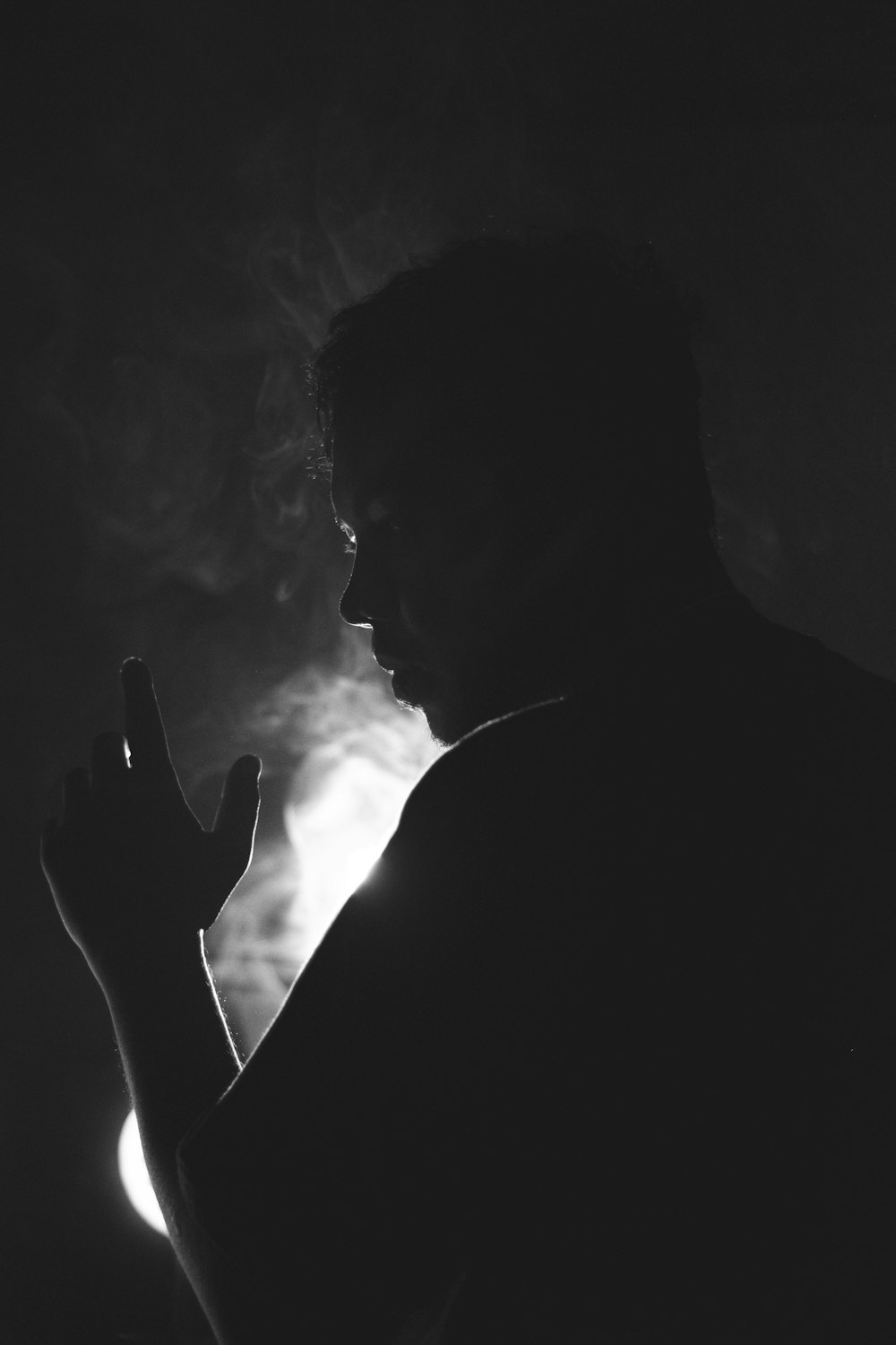 a man smoking a cigarette in the dark