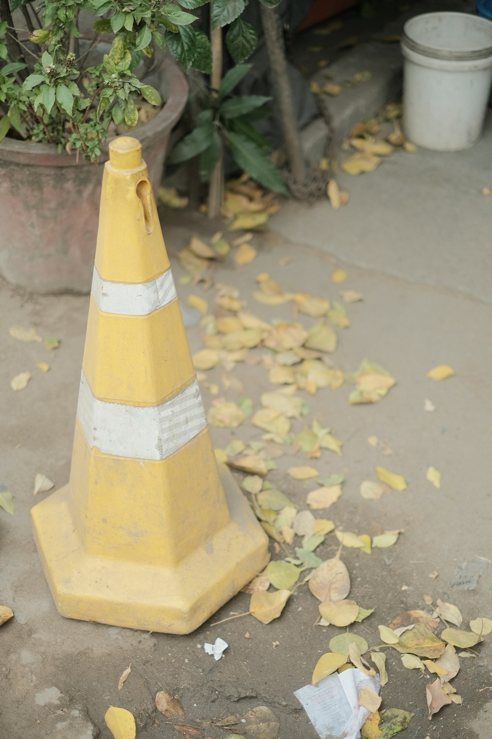 a traffic cone sitting on the ground next to a potted plant