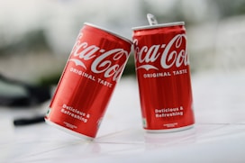 two cans of coca cola sitting on a table