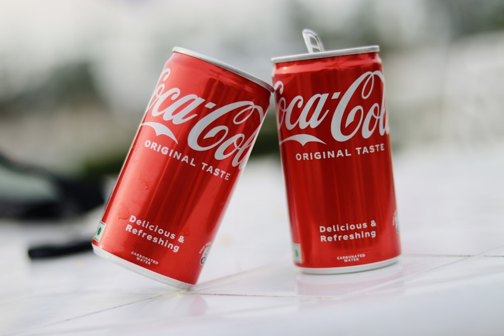 two cans of coca cola sitting on a table