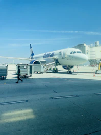 Airport ground staff assisting passengers near a boarding gate under bright daylight.