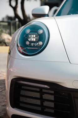 Close-up of a sleek car headlight glowing with bright white LED light on a dark road.