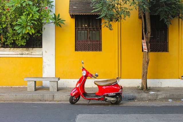 a red scooter parked next to a yellow building