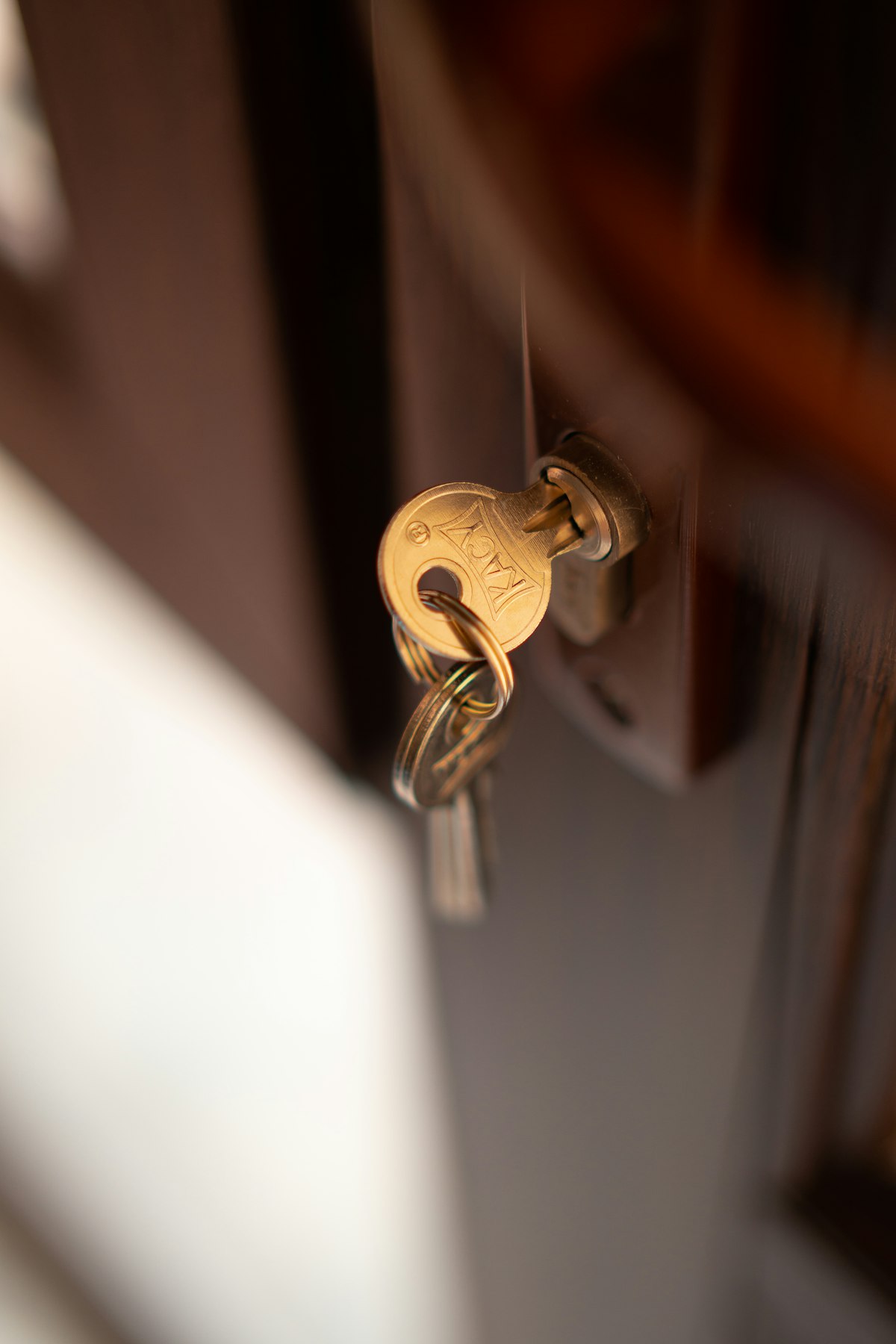 Close-up of a brass key inserted into a lock on a dark wooden door