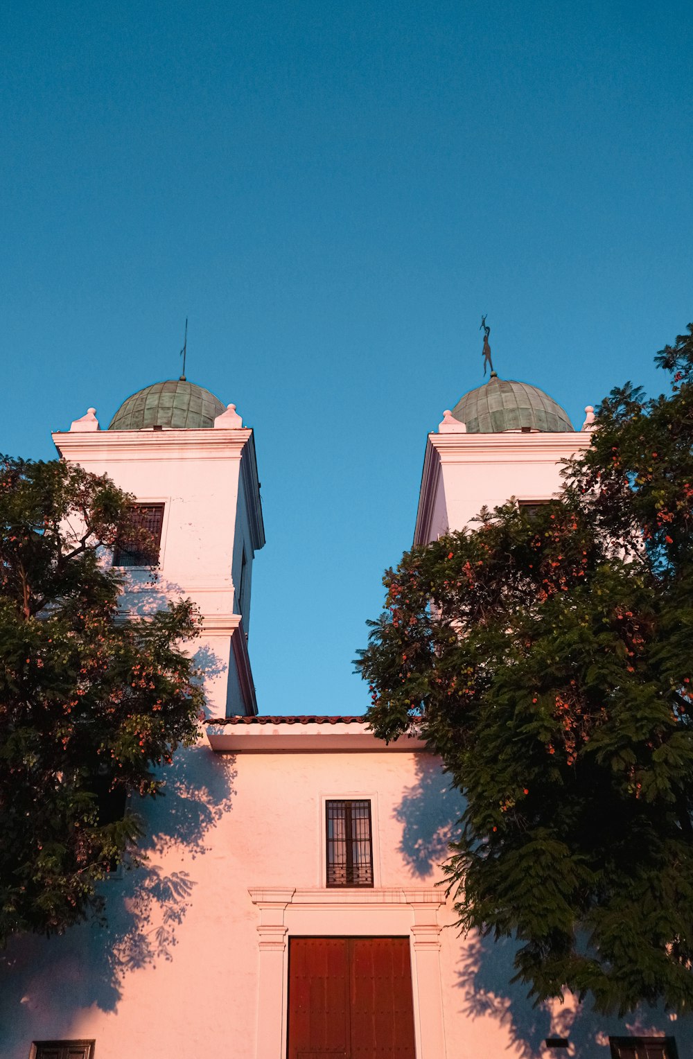 a white building with two towers and a red door