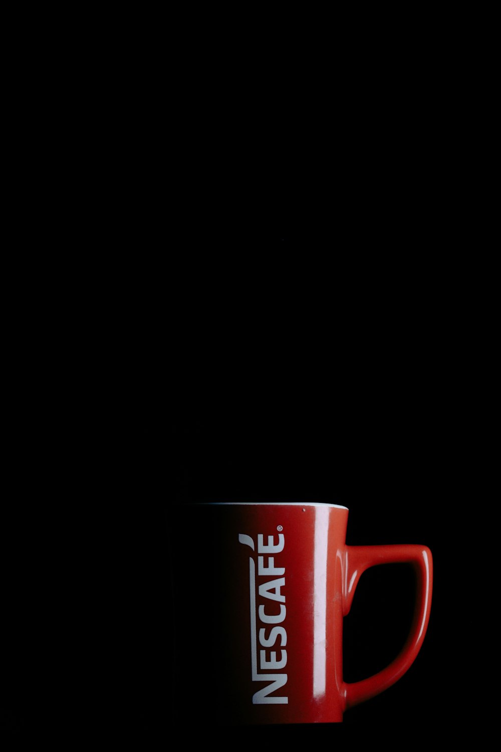 a red and white coffee cup sitting on top of a table