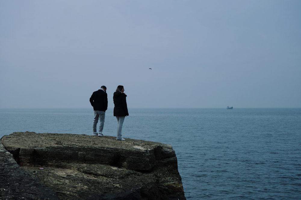 a couple of people standing on top of a cliff