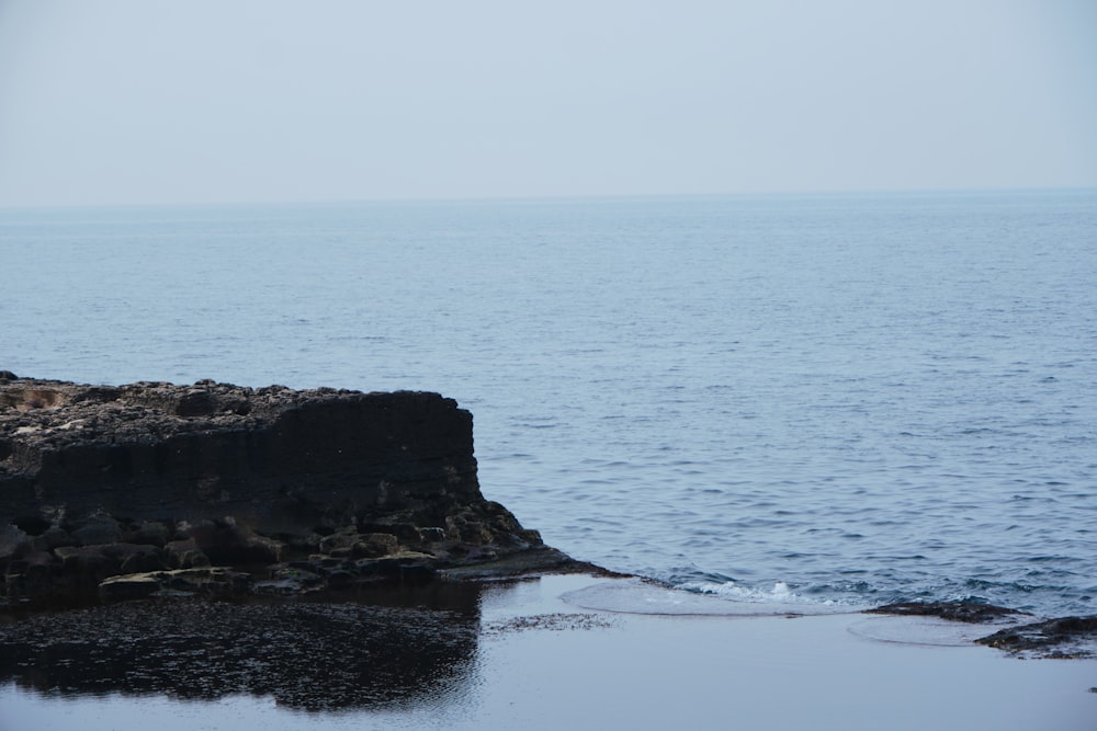 a person standing on a rocky outcropping near the ocean