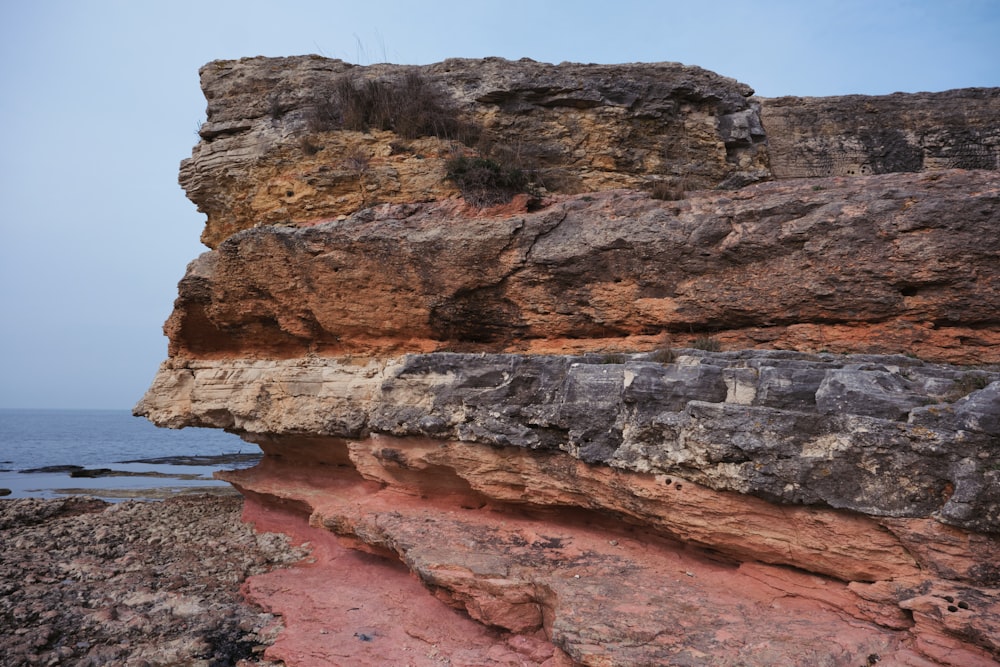 a rocky cliff with a red and white substance on it
