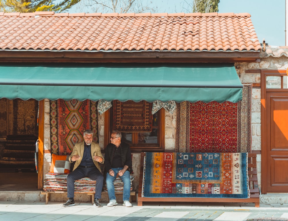 two people sitting on a bench in front of a store