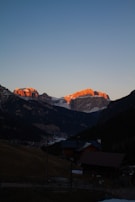 Evening shot of a fire-safe prefab cottage glowing softly against a mountainous backdrop.
