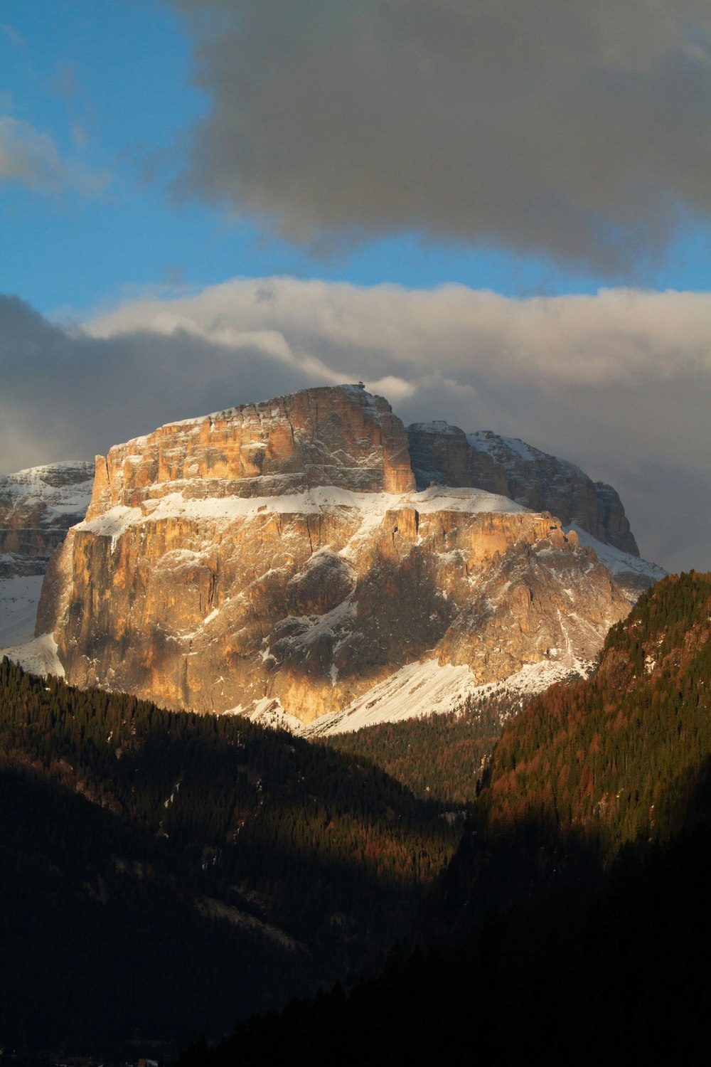 a snow covered mountain with a few clouds in the sky