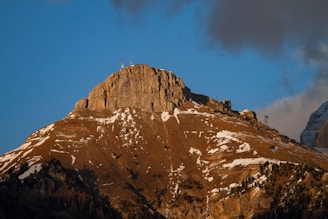 A rugged mobile telecom unit being set up on a rocky mountain ridge at sunrise.
