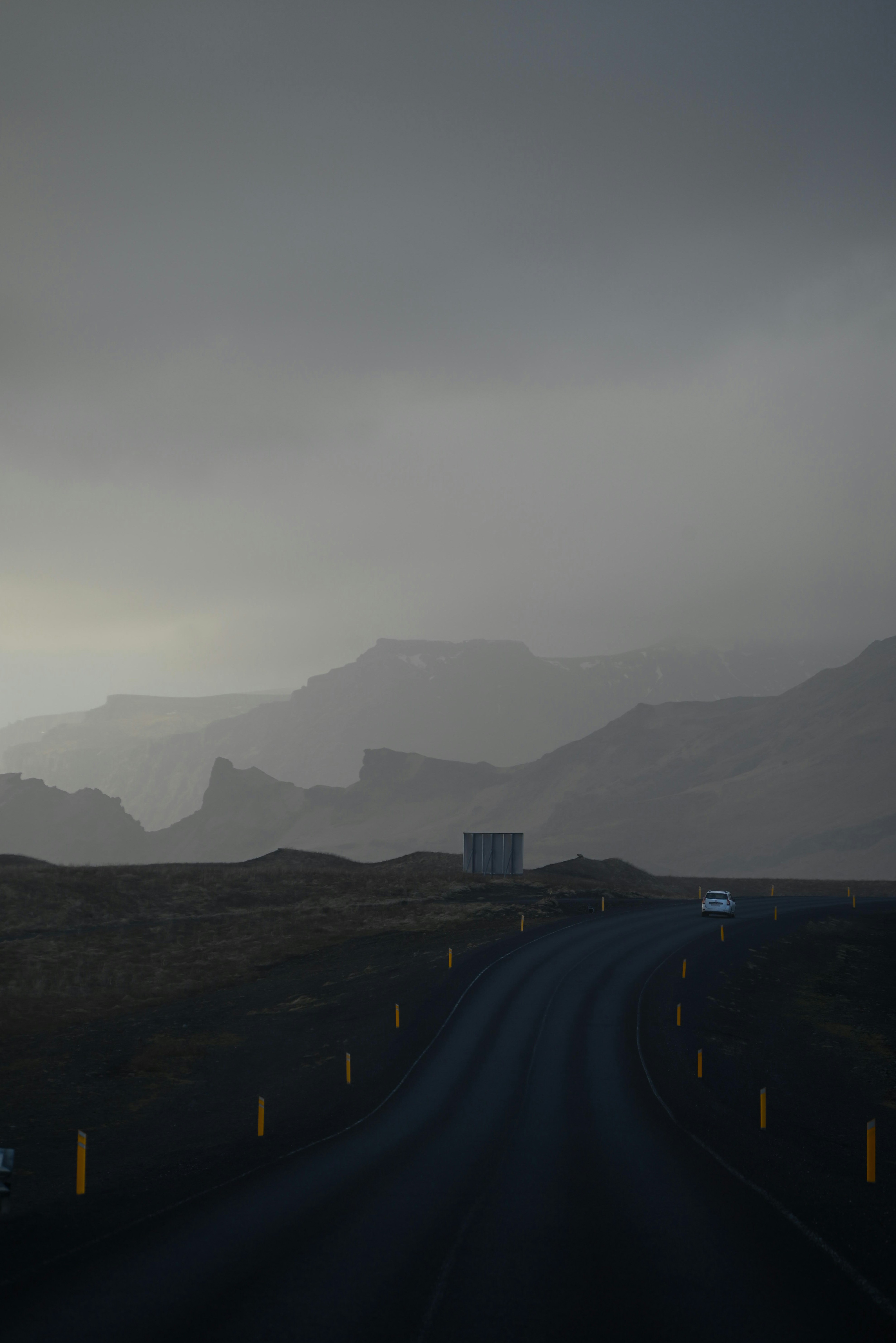 a dark road with mountains in the background