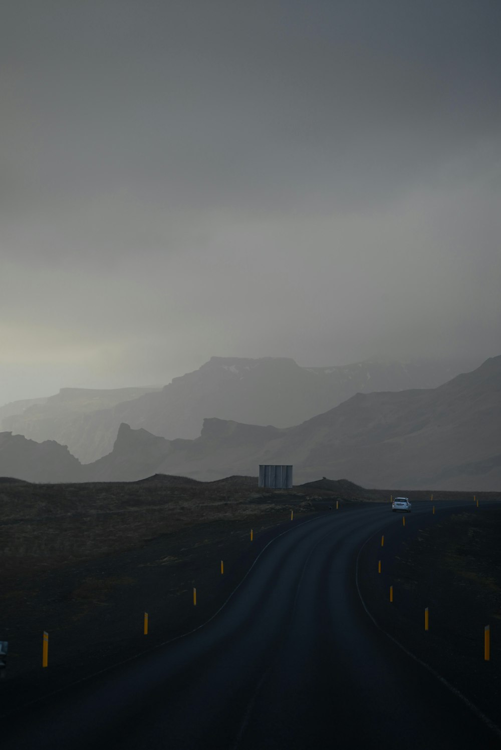 a dark road with mountains in the background