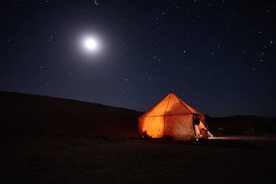 A cozy desert tent glowing warmly against a starry night sky.