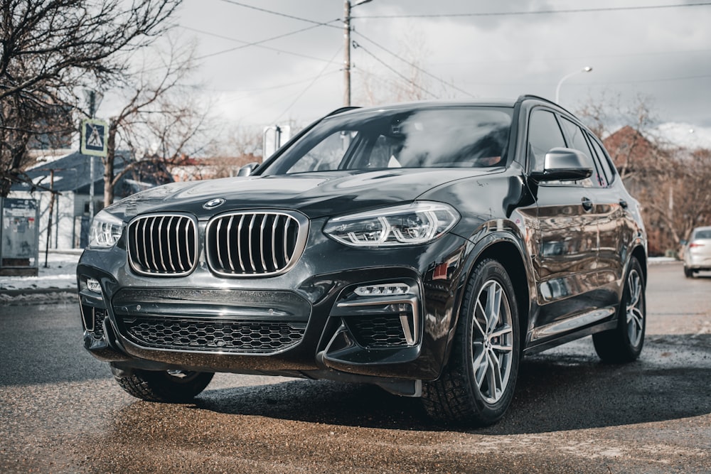 a black bmw suv parked in a parking lot