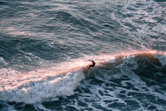 A vibrant photo of a surfer catching a wave at sunrise, embodying the adventurous spirit of Bright Eye.