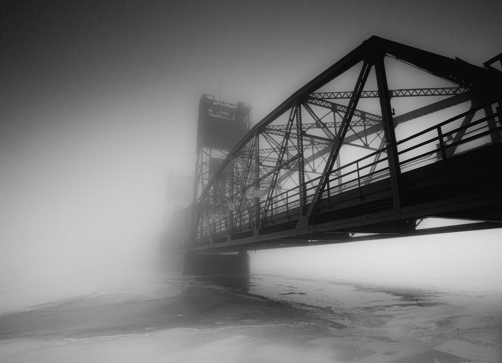 a black and white photo of a bridge on a foggy day