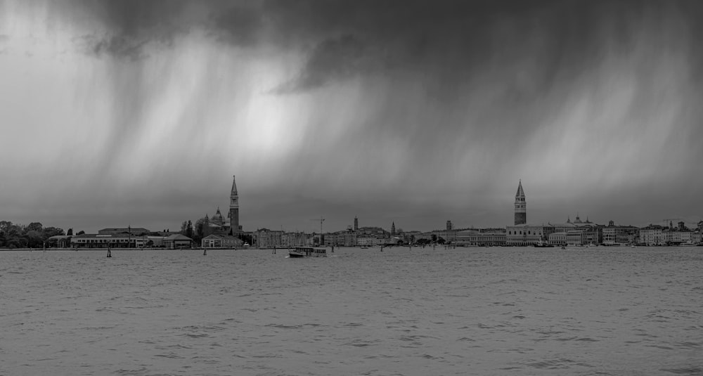 a black and white photo of a storm moving over a city