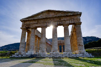 the sun shines brightly behind the ruins of a temple