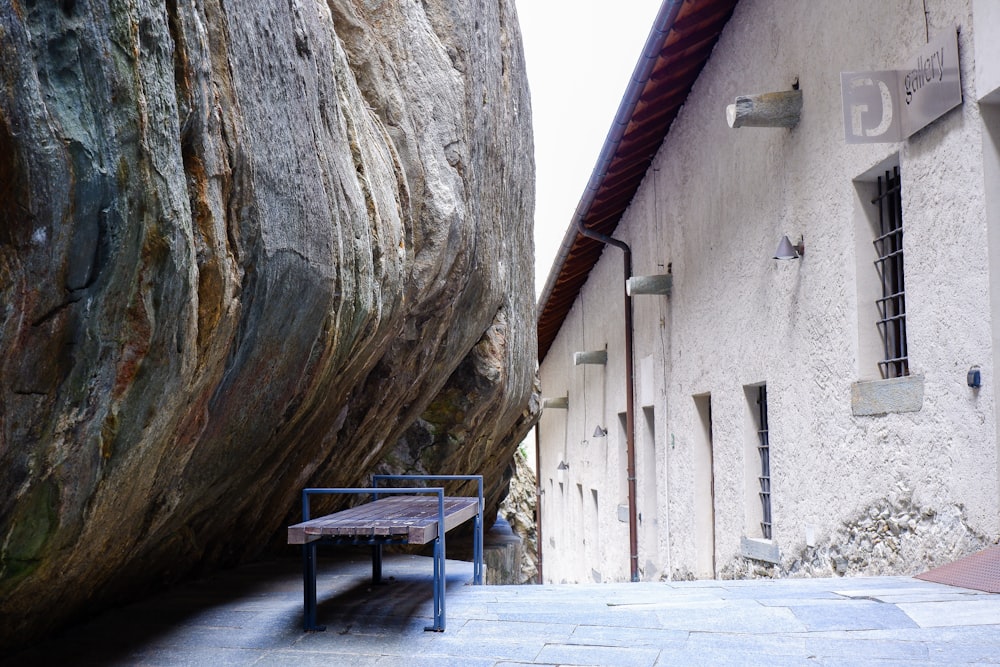 a bench sitting next to a large rock