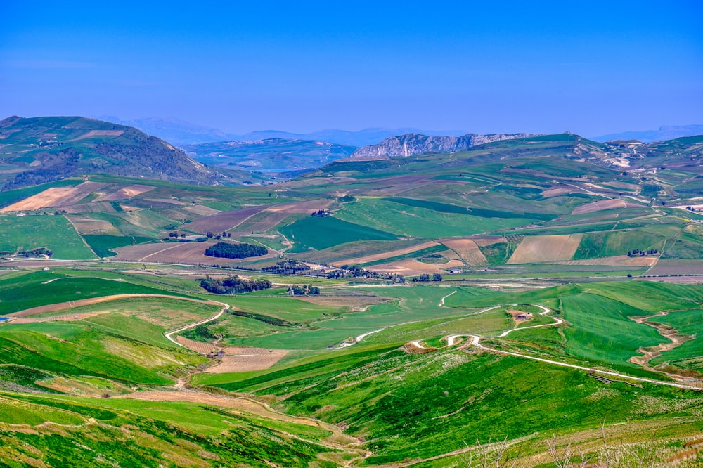 a scenic view of a green valley with mountains in the background